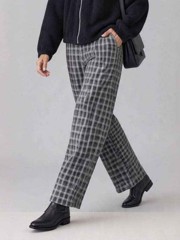 Grijze Chastar broek Linette met contrasterende ruiten en lange pijpen, in driekwartaanzicht met zwarte laarzen.