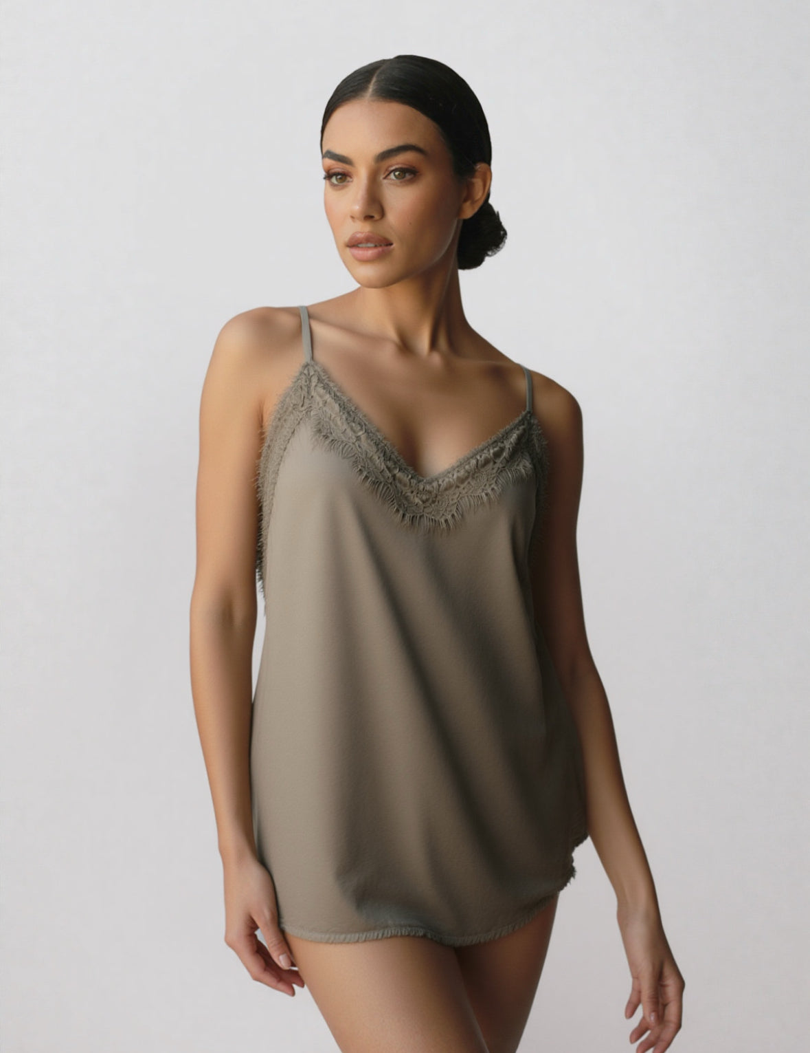 Taupe top met spaghettibandjes en een kanten rand langs de V-hals, gedragen door een model.