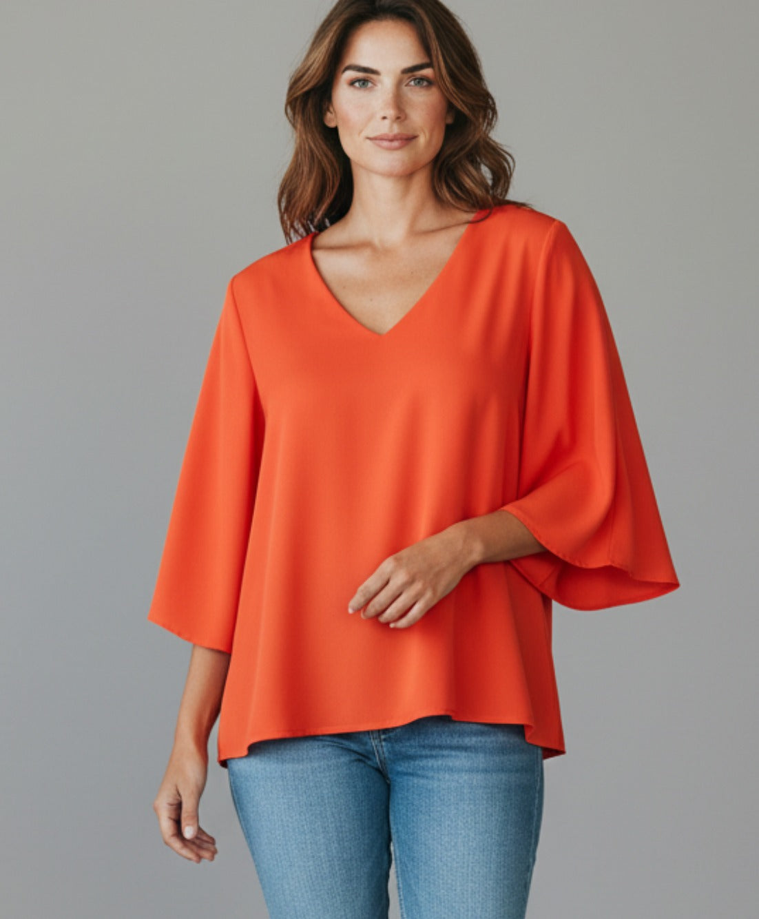 Rode top van zijde en viscose met V-hals en uitlopende mouwen, gedragen door een model met jeans.